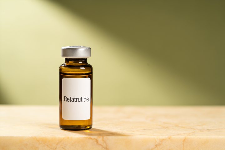 Amber pharmacy vial labelled Retatrutide on warm marble, illustrating a metabolic optimization compound discussed in this educational article